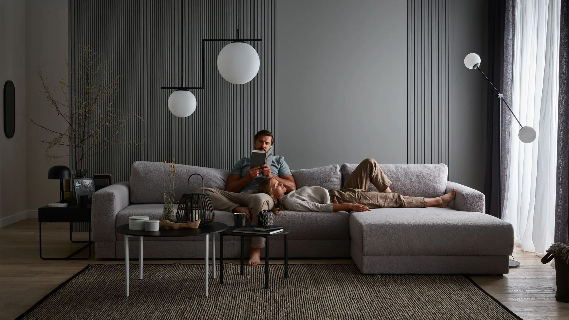 Nowoczesny salon z minimalistycznymi kulistymi lampami i szarą sofą.
